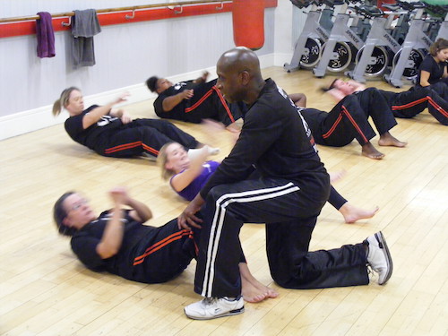 Rob helps a student with a sit up whilst on the ground at Richmond Olympus Gym